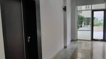 A hallway with a dark door and a glass entrance leading to an outdoor area.