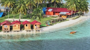 A beachfront property with wooden huts, a sandy beach, and clear turquoise waters. - Pelicano Island (Moraquedub)
