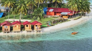 Una propiedad frente a la playa con cabañas de madera, una playa arenosa y aguas turquesas cristalinas.