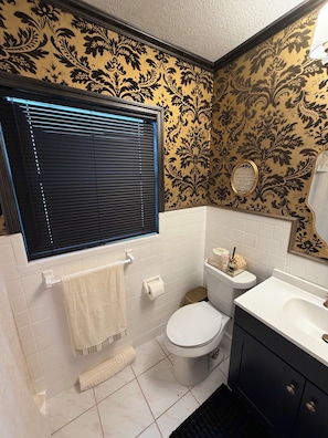 Een badkamer met toilet, wastafel en raam met zonwering.