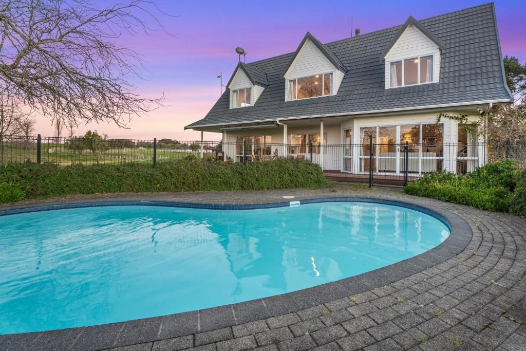 Una casa con piscina, rodeada por una cerca y vegetación.