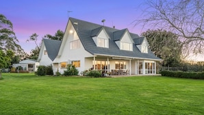 A two-story house with a large front lawn and a covered patio area. - The Pond House by Homello (Karaka)