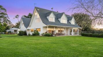 Una casa de dos pisos con un amplio jardín delantero y un porche cubierto.