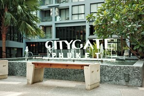 A bench with the words 'CITYGATE PHUKET' in the foreground, a modern building with large windows in the background, and a water feature with multiple fountains. - Kamala - Peaceful Courtyard (Kathu District)