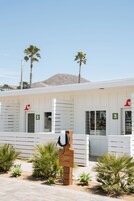 A modern building with numbered rooms, palm trees, and a clear sky.