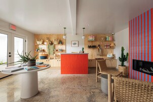 Una cocina moderna con una isla central, armarios de madera y una pared de acento roja.