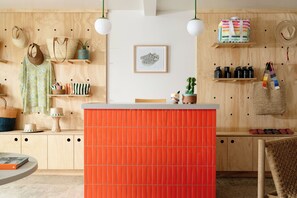A room with a wooden wall, a central orange partition, and various items like bags, a hat, and a framed picture.