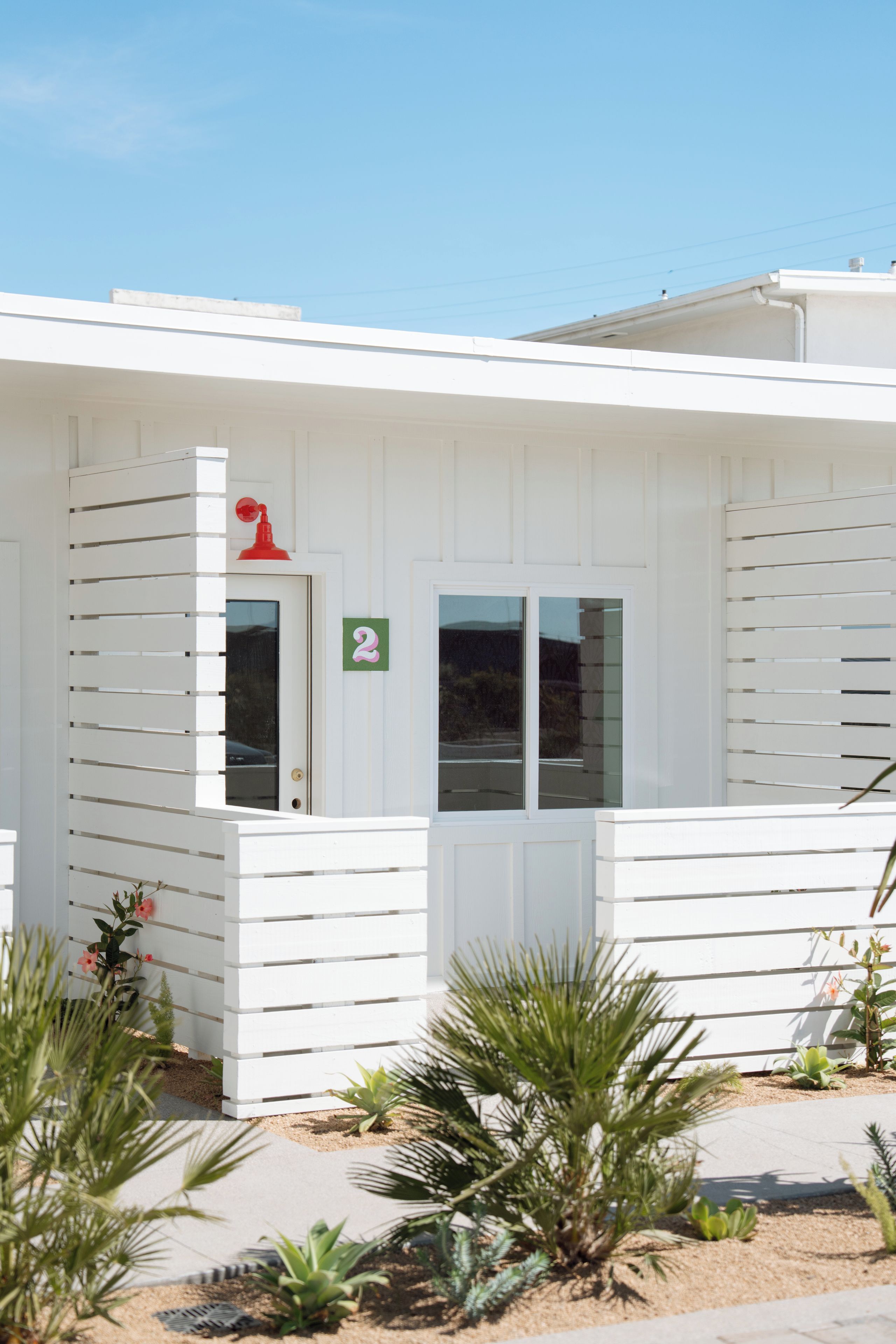 A white building with a number 2 sign, a door, and windows.