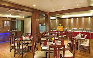 Un restaurante con varias mesas, sillas y una zona de bufé.