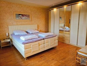 A bedroom with a bed, bedside table, and a wardrobe with mirrors.