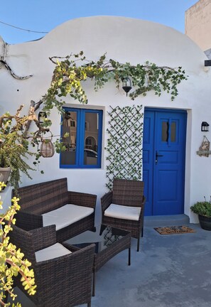 A white building with a blue door and windows, surrounded by greenery and wicker furniture. - Casa Calma House (Emporio)