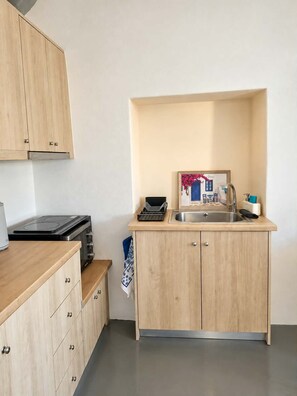 A compact kitchen with a built-in stove, a sink, and wooden cabinets. - Casa Calma House (Emporio)