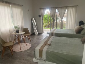 Een hotelkamer met twee bedden, een kleine tafel met stoelen, een potplant en uitzicht op het landschap.