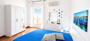 Quarto com cama, guarda-roupa, mesa de cabeceira e um quadro de uma cena de canal.