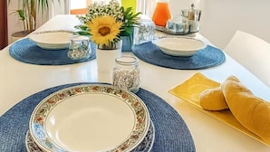 Una mesa de comedor dispuesta con platos, un florero con flores, una jarrón de vidrio y una botella.