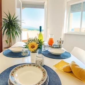 Mesa posta com pratos, um vaso de flores, um jarro de vidro e uma garrafa.