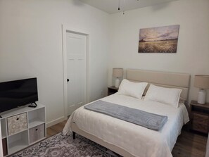 Een slaapkamer met een bed, een televisie, een schilderij en een kamerkleed met patroon.