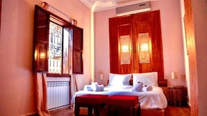 A hotel room with a large bed, two bedside tables, a window with curtains, and a radiator. - Riad Rêve D'antan Dream (Marrakech)