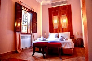 A hotel room with a large bed, two bedside tables, a window with curtains, and a radiator. - Riad Rêve D'antan Dream (Marrakech)