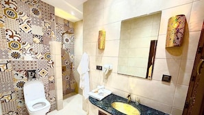 A bathroom with a patterned tile wall, a white toilet, a sink with a gold faucet, and a mirror with decorative lights. - Riad Rêve D'antan Dream (Marrakech)