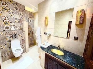 A bathroom with a patterned tile wall, a white toilet, a sink with a gold faucet, and a mirror with decorative lights. - Riad Rêve D'antan Dream (Marrakech)