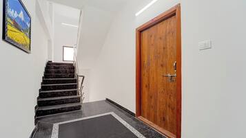 Un pasillo con una puerta de madera, una escalera y un cuadro en la pared.