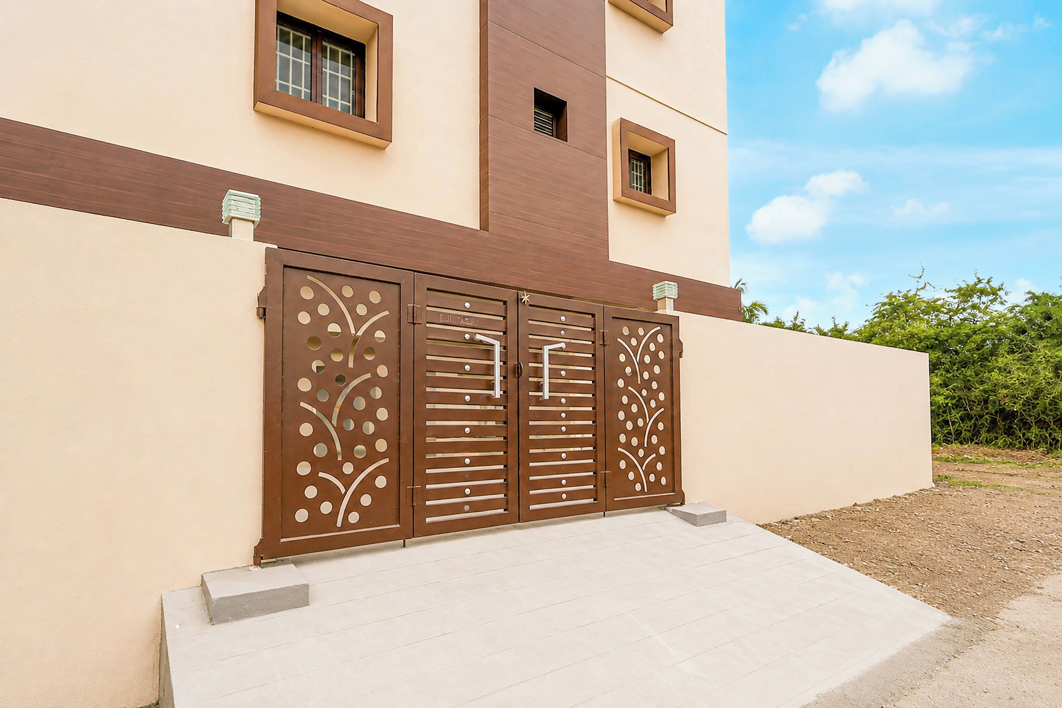 Un edificio moderno con fachada color beige, una puerta marrón con detalles decorativos y un pequeño ventanal encima de la puerta.