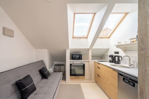 A compact kitchen with a built-in oven, microwave, and modern appliances. - Stylish 2-BR Loft | AC, Cheap parking & Sleeps 6 (Riga)