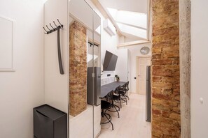 A modern kitchen with a dining area, a built-in TV, and a brick wall. - Stylish 2-BR Loft | AC, Cheap parking & Sleeps 6 (Riga)