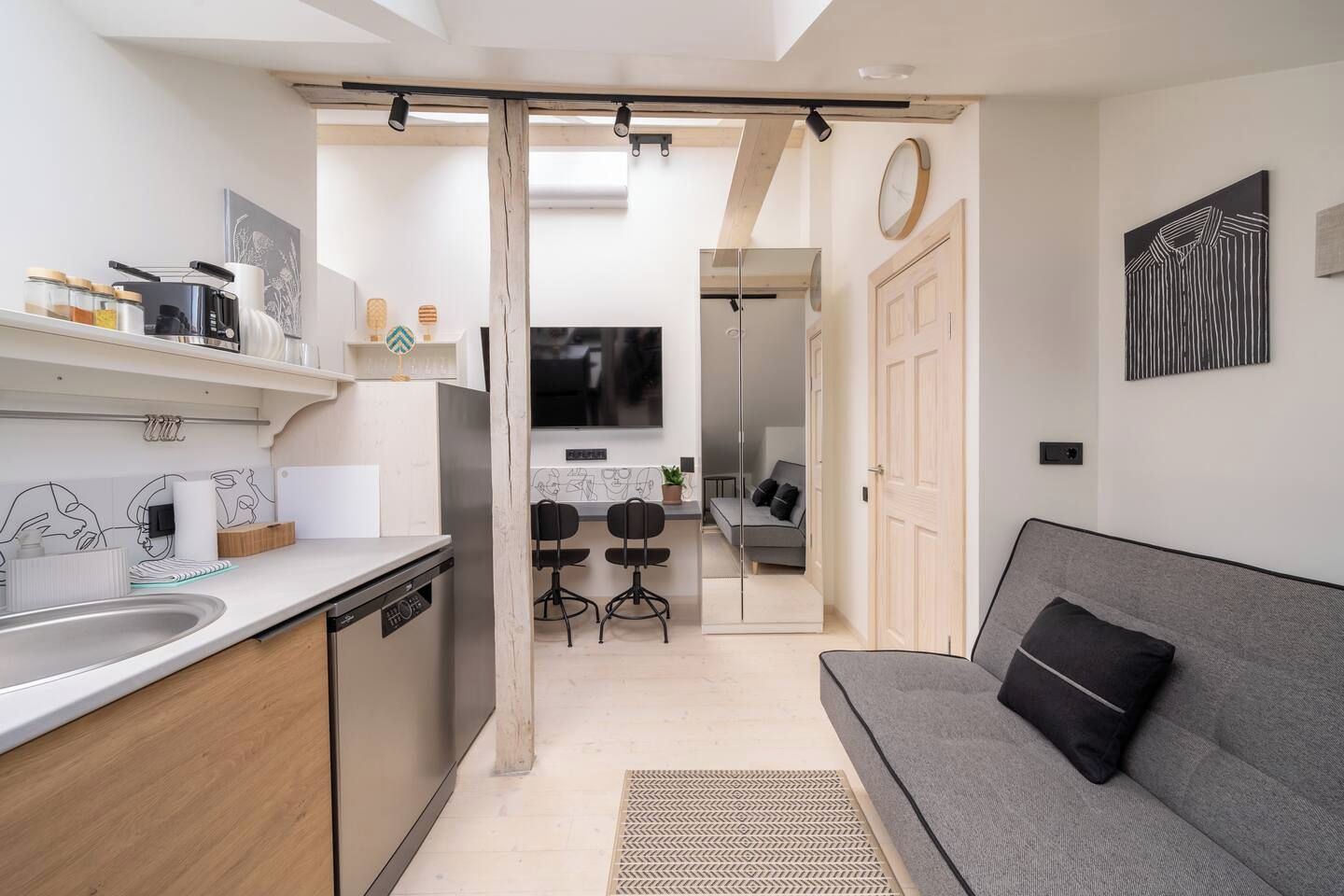 Una cocina moderna con comedor, sofá y puerta de armario espejada.