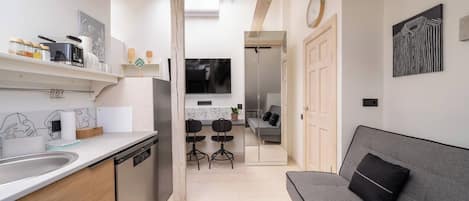 Una cocina moderna con comedor, sofá y puerta de armario espejada.