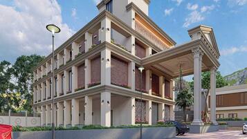 A multi-story hotel with a central courtyard, balconies with flower boxes, and a classical entrance with columns.