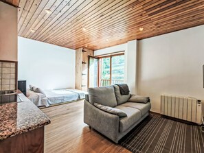 Een modern interieur met een houten plafond, een bank, een bed en een keukenhoek.