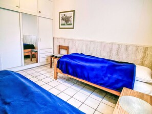 A bedroom with two beds, a wooden chair, a wardrobe, and a framed picture on the wall. - Vacation home Rhena by Interhome (Norddeich)