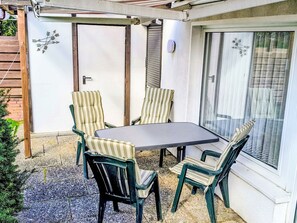 A patio with a table and chairs, a door, and a window with a view. - Vacation home Rhena by Interhome (Norddeich)