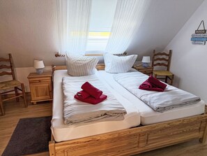 A double bed with white linens, two bedside tables with lamps, a wooden headboard, and a small rug. - Nordziel by Interhome (Norddeich)