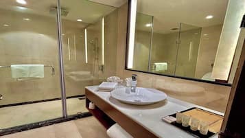 Un baño moderno con cabina de ducha de vidrio, un lavabo redondo y un espejo grande.