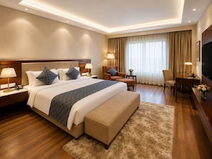 Una habitación de hotel con una cama grande, un sofá, una silla, un escritorio y una televisión.