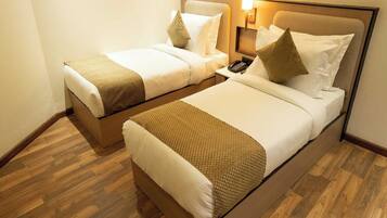 A hotel room with two beds, each with a headboard, pillows, and a bedside table with a phone.
