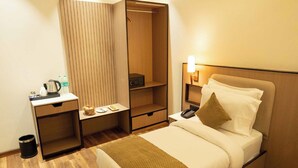 Une chambre d’hôtel comprenant un lit, une table de chevet, un bureau avec une bouilloire, un four à micro-ondes et une armoire.