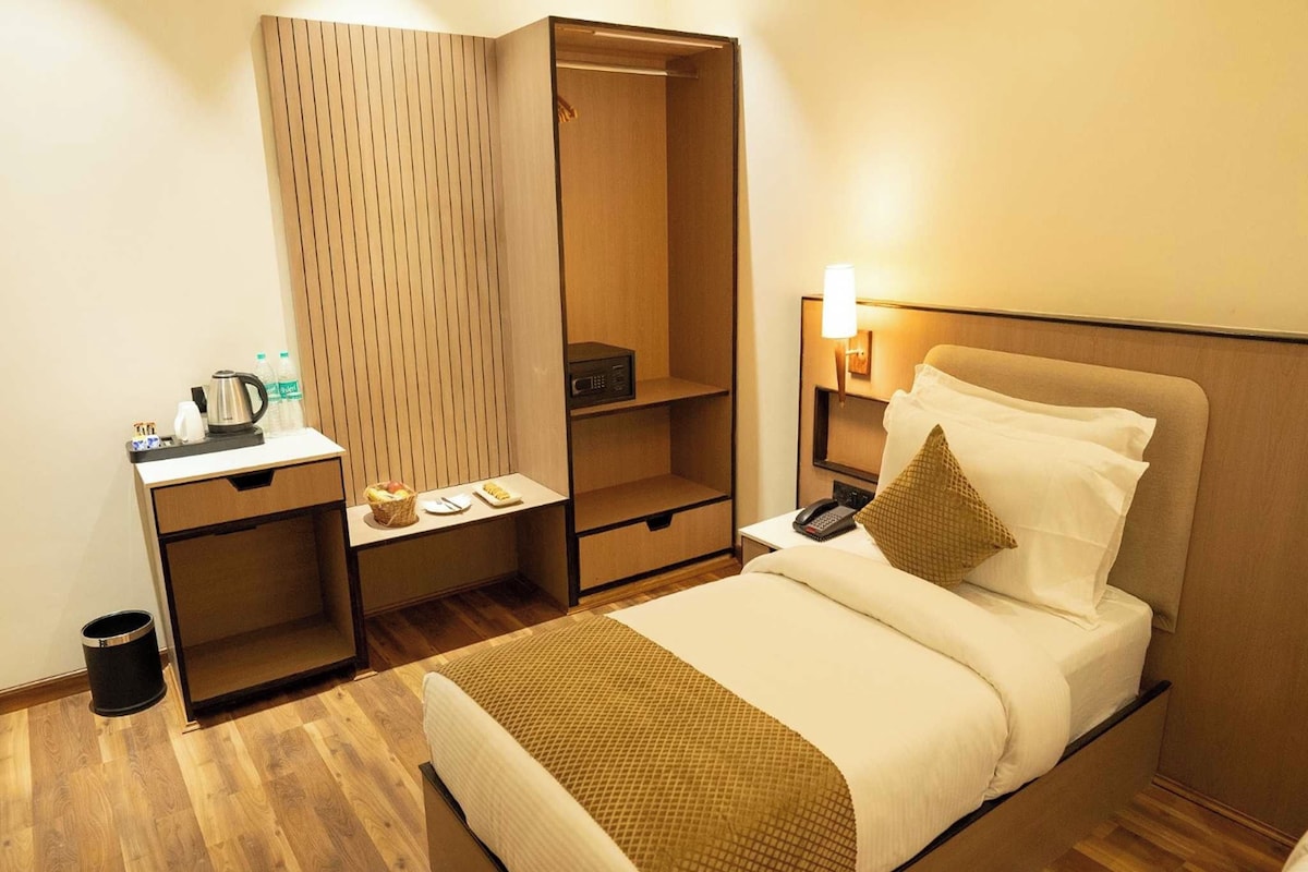 Une chambre d’hôtel comprenant un lit, une table de chevet, un bureau avec une bouilloire, un four à micro-ondes et une armoire.