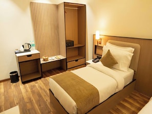 Une chambre d’hôtel comprenant un lit, une table de chevet, un bureau avec une bouilloire, un four à micro-ondes et une armoire.