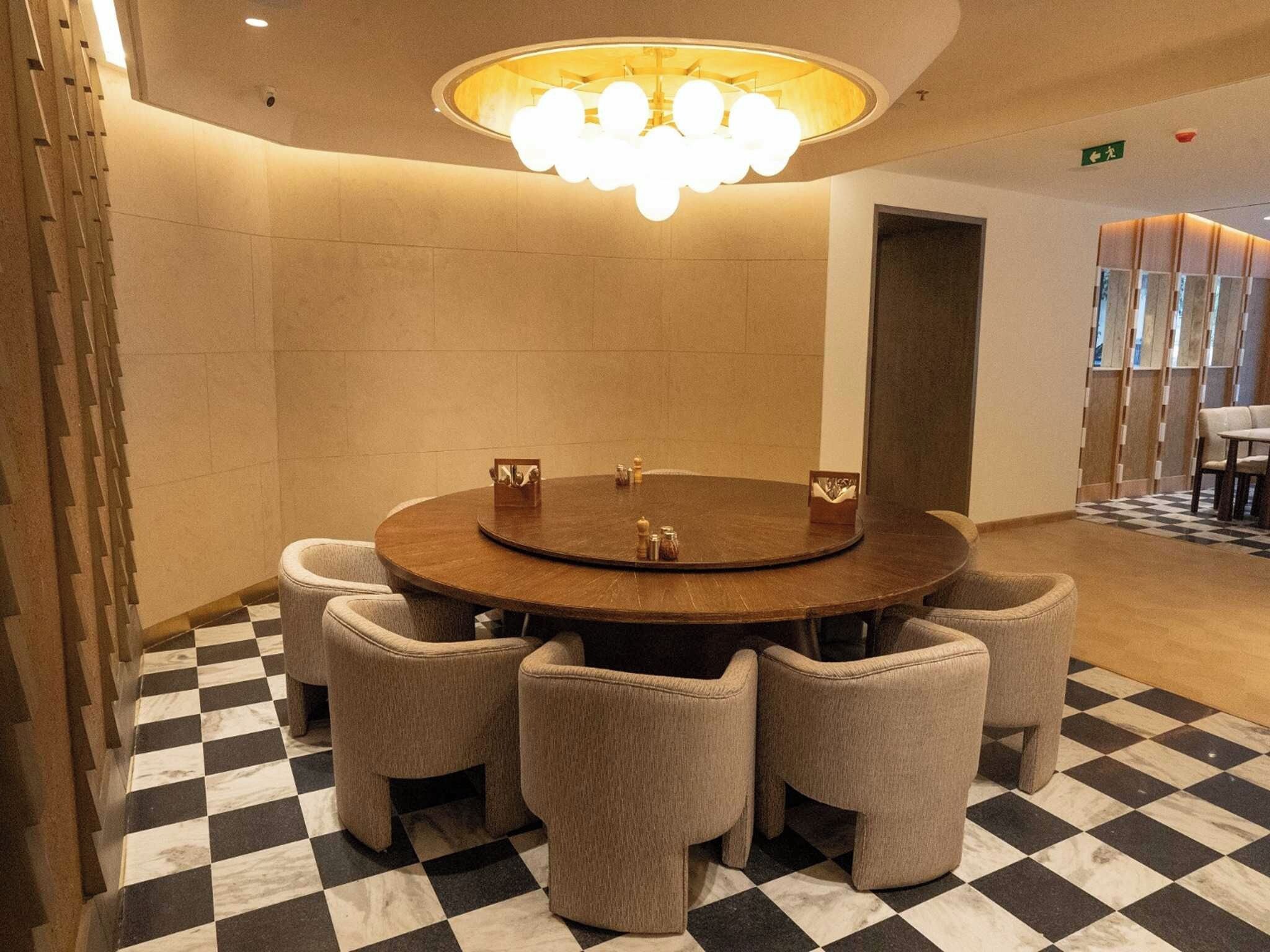 A conference room with a round table, six chairs, a chandelier, and a checkered floor.