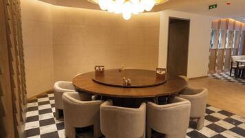 A conference room with a round table, six chairs, a chandelier, and a checkered floor.