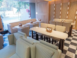 A hotel lobby with a checkered floor, seating areas, and a view of the street. - Palette Hotel by CheckIn Amritsar City (Amritsar)
