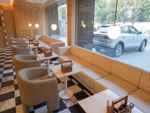 A restaurant with checkered flooring, cushioned seating, and tables with napkin holders. - Palette Hotel by CheckIn Amritsar City (Amritsar)