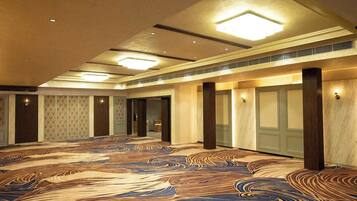A spacious hall with a patterned carpet, recessed lighting, and a symmetrical layout with columns.