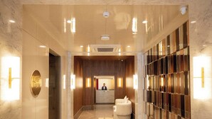Un hall d’hôtel comprenant un comptoir d’accueil, un espace salon et un mur orné d’un motif décoratif.