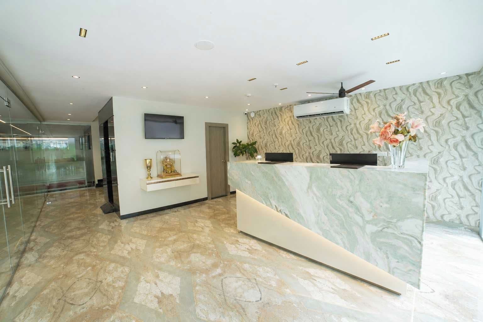 Un área de recepción moderna con mostrador de mármol, televisor de pantalla plana y ventilador de techo.
