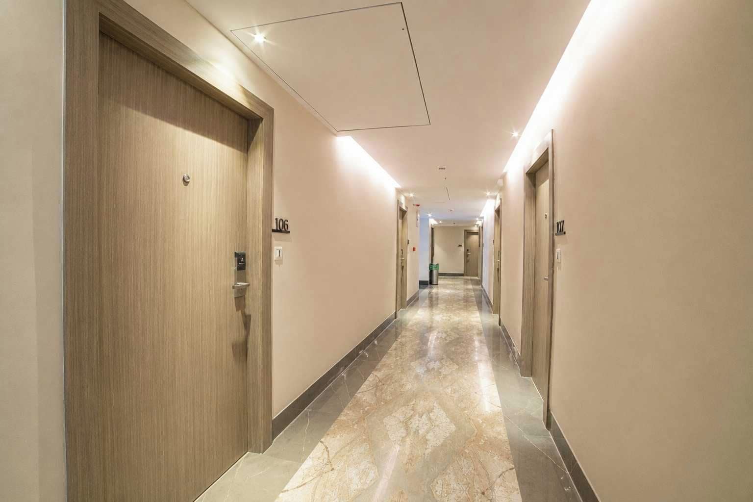 A hotel hallway with doors numbered 106 and 107, marble flooring, and recessed lighting.